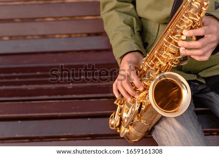 Man playing Golden saxophone in the street. Saxophone and jazz day concept. Top horizontal view copyspace
