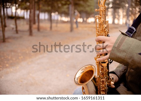 Man playing Golden saxophone in the street. Saxophone and jazz day concept. Top horizontal view copyspace
