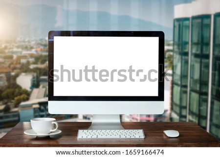Workspace with computer Monitor, Keyboard, blank screen coffee cup smartphone, and tablet on a table or White Screen Isolated in bright office room interior.
