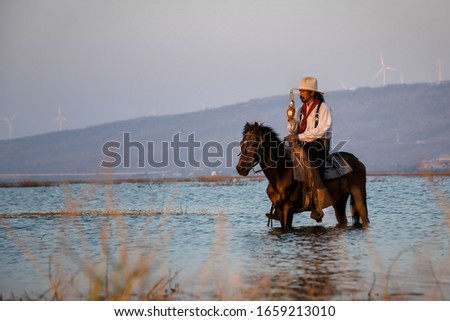 Man cowboy riding a horse, crossing the river