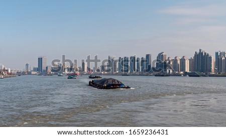 Cargo ship sailing on Huangpu river with Shanghai skyline background.