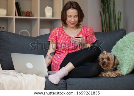 Beautiful woman are buying online with a credit card and smile while sitting on the sofa at home. Woman are using laptop and doing online transactions, Past the internet
