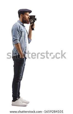 Full length profile shot of a bearded guy recording with a vintage camera isolated on white background