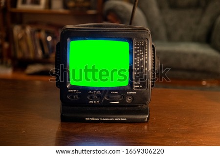 An Old mini black and white Television powered on and stand on table of real home at night green screen