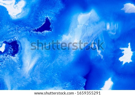 Classical blue and white watercolor paint in abstract spreading forms similar to satellite imagery with arctic snow hills and seas with glaciers melting in macro. Stains of paint in macro for design.