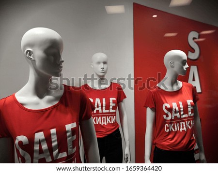 Monikeny in a shopping center behind a shop window against a white and red wall in red polo sweatshirts with the inscription sale on the day of big discounts