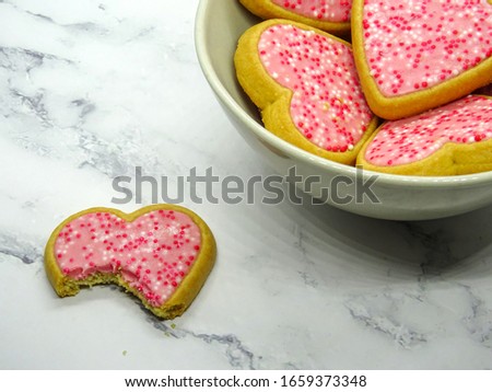 Heart cookies in a plate and one bitten cookie, temptation concept
