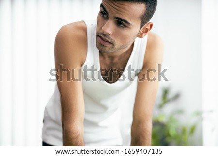 Young man wearing white t-shirt and looking away in his apartment stock photo