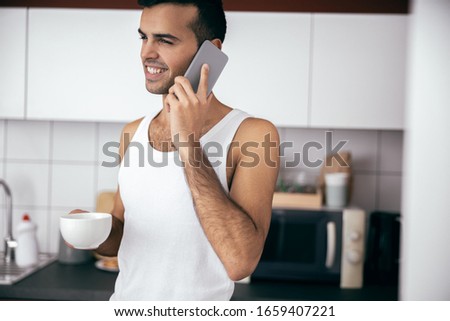 Happy handsome guy talking on smartphone in the morning at home stock photo