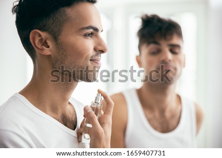 Smiling young male spraying perfumes with his brother on the background stock photo