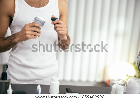 Cropped photo of male in white t-shirt opening antiperspirant while staying at home stock photo