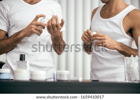 Cropped photo of male twins standing together while holding hand cream and vitamins stock photo
