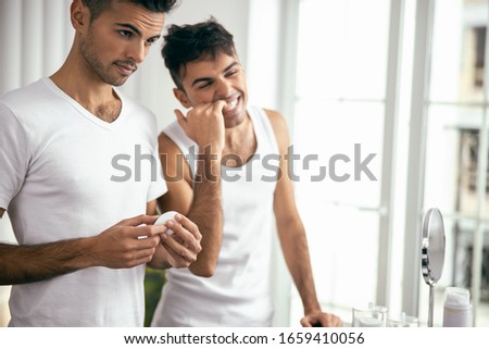 Handsome man holding dental floss while his brother standing near him stock photo