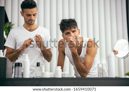 Waist up of guy doing manicure while his brother standing next to him stock photo