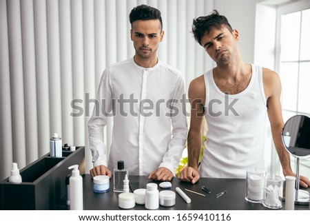 Waist up of man in shirt and another one in white t-shirt standing in room stock photo