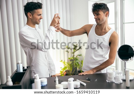 Happy twins testing male fragrance at home stock photo