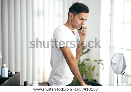 Waist up of handsome man using mobile phone in his flat stock photo