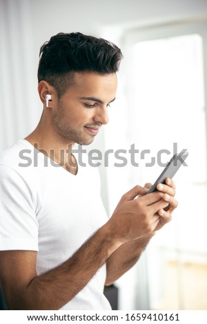 Happy handsome guy listening music while using smartphone at home stock photo