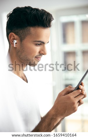 Waist up of happy handsome man with wireless headphones listening music stock photo