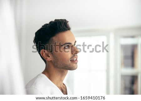 Side view of handsome guy standing and looking away in room stock photo