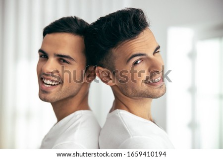 Waist up of happy handsome twins posing in flat stock photo