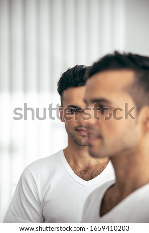 Cropped photo of of smiling male twins in t-shirts posing in room in their flat stock photo