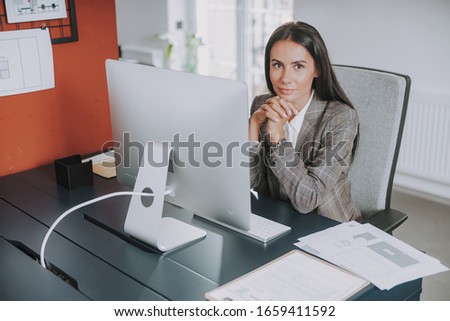 Smiling woman sitting near computer stock photo