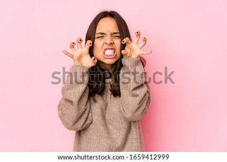 Young mixed race hispanic woman isolated showing claws imitating a cat, aggressive gesture.
