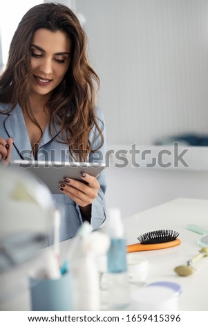 Smiling beautiful lady in pajamas using digital tablet at home stock photo