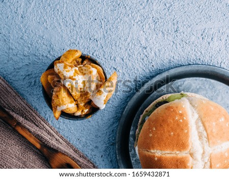 Soya vegan burger with french fries with spices and sauce in a metal bowl on blue table background