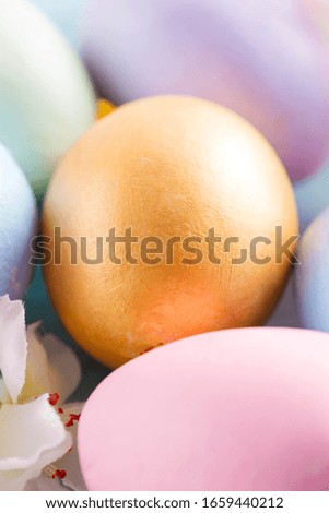 Greeting Easter card with close-up golden painted eggs on a light blue background.