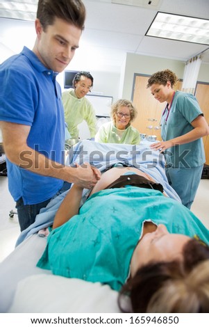 Caring mid adult man holding woman's hand during delivery in hospital room