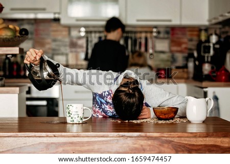 Tired mother, trying to pour coffee in the morning. Woman lying on kitchen table after sleepless night, trying to drink coffee Royalty-Free Stock Photo #1659474457