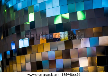 Colorful square metallic tiles on a wall or floor. Blue, green, teal, yellow, orange, purple reflective tile pattern. Shiny tile pattern with purple, teal, green, blue, yellow, gold and orange