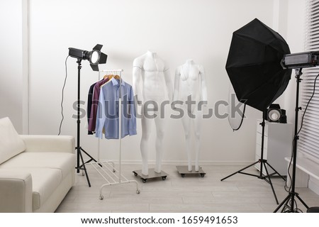 Ghost mannequins, clothes and professional lighting equipment in modern photo studio Royalty-Free Stock Photo #1659491653