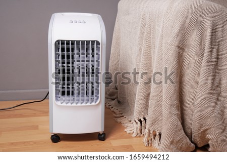 portable air cooler and humidifier on casters in domestic living room to improve indoor clmate Royalty-Free Stock Photo #1659494212