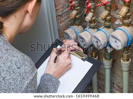 Woman checking the readout on a water meter. Household water consumption, cost of water concept image. Royalty-Free Stock Photo #1659499468