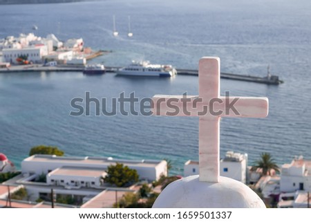 Panorama of sunset above Mykonos town harbor with Greek Orthodox church cross in front. Old windmills (Kato Mili)- famous landmark and tourist attraction on background. Ships on Aegean sea, Cyclades