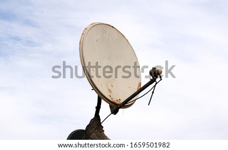 Satellite dish antenna over blue sky and roof background