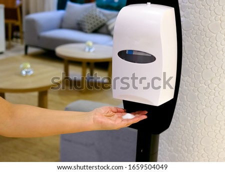 Closeup of Hands under the automatic alcohol dispenser. Sanitation station for cleaning of hands. Infection prevention concept. Selective focus closeup.  Royalty-Free Stock Photo #1659504049