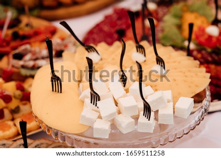 Festive table with dishes. Dish. Sliced cheese with honey on a white plate. Cheese, grapes and honey on the table. Delicious dishes on the table in the restaurant. Cheese. Food.