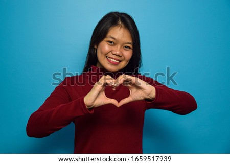 Portrait of Young beautiful asian women with blue isolated background, Make love with hands, Love Gesture