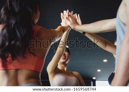 A group of young Asian people who are in good shape at the gym. Picture of cheerful fitness team in gym.They coordinated their hands. Concepts of exercise for health and good shape