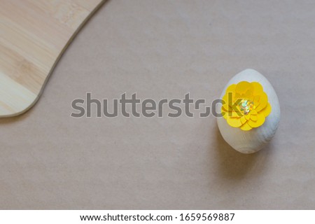 Wooden Easter egg with a yellow flower on a natural background.