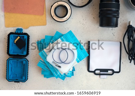 Video light, lens filters, including polarizer, gradient and adapter rings, and a box with flash drives on grey backgrond. Flat lay composition with equipment for professional photographer