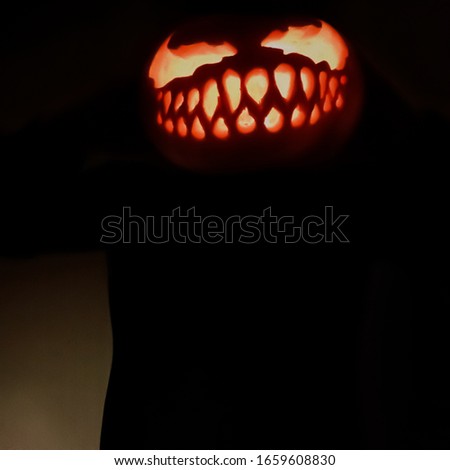 A creepy man with a Jack lantern instead of a head. Pumpkin instead of the head.  Halloween lantern. Pumpkin with a carved face and burning eyes. Creepy costume