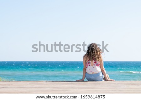 Seaside, Florida wooden boardwalk during sunny day in panhandle town village beach with ocean high angle steps and horizon and woman sitting