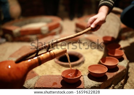 Person pouring wine from qvevri using Orshimo, Georgia Royalty-Free Stock Photo #1659622828