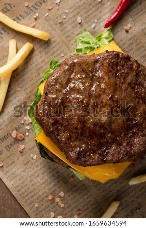 A tasty grilled juicy burger with beef, onion, cheese,  and lettuce. Top view with copy space