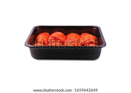 Grilled legs. Isolate.Raw chicken marinated legs in a black plastic package on a white background. Raw chicken marinated meat in a package.